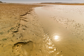 Reflection of Sun in the water of river, river bed landscape of Tajpur with tree lines and horizon in the background. West Bengal, India