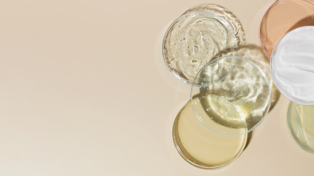 Various Cosmetic Products In Petri Dishes On Beige Background View From Above. Copy Space