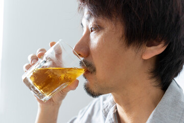 Close up of adult asian man enjoy drinking glass of liquor.