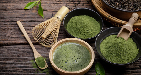 Japanese organic matcha green tea powder in bowl with wire whisk and green tea leaf on wooden...