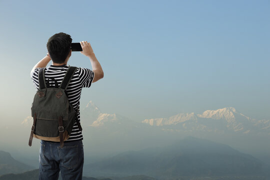 A young traveler man on the top of iceberg iceberg mountain with backpack in the nature and take a photo with smartphone the beauty of landscape, Adventure and travel in the mountains region concept