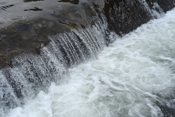 Fototapeta na wymiar Small waterfall with clear water closeup