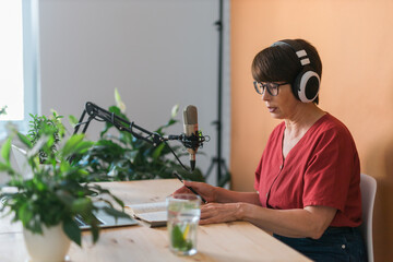 Middle-aged female radio presenter talking into the microphone and reading news - radio broadcast...