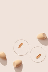 Beauty blender make up sponge for foundation cream, samples on glass disk, sponges on beige color background with hard light. Skincare beauty product. Swatches from tone cream and makeup puff