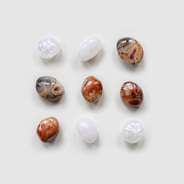 Creative arrangement of natural colored stones. Smooth round pebbles as square pattern on light white background. Minimal summer flat lay, top view  composition with different gemstones
