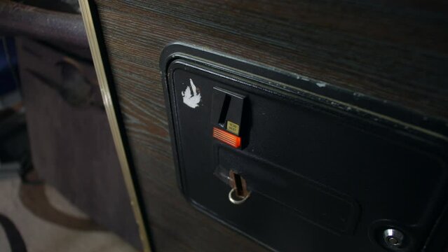 A man inserting a coin into an arcade machine coin mech - Powered by Adobe