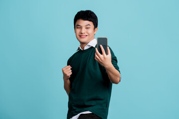 Handsome asian showing pleased after trying use new application, holding mobile phone, leave positive feedback on app