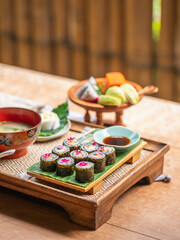 Sushi platter with edible flowers Presented on a wood tray with miso soup and mixed fruit, Selective focus. Healthy Japanese food, food concept.