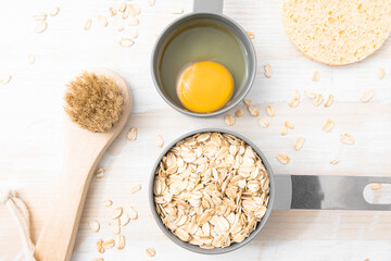 Ingredients for a homemade cosmetic mask on a wooden table. Oatmeal and egg for strengthening hair...