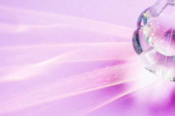 A glass vase on a light lilac background with hard shadows and sun glare. Reflection of light from glass. Abstract background