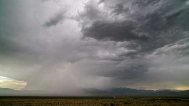 Timelapse of dark rainstorm in the desert as traffic drives away with lightning strike.