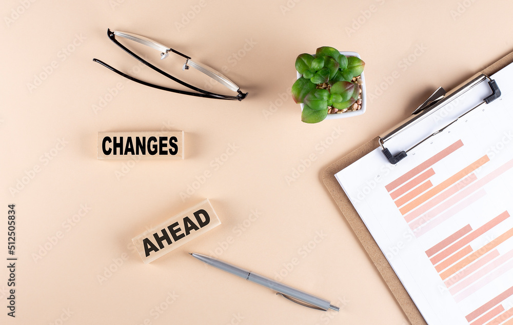 Poster changes ahead text on wooden block with chart and glasses, business concept