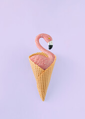 Minimal summer composition with flamingo standing in in ice cream cone on isolated pastel purple background. Summer vacation concept. Top view.  © jbuinac