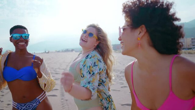 Beautiful multiethnic young women having fun on the beach during the summetime vacation. Storytelling representation of body positivity, self acceptance and individuality female concepts