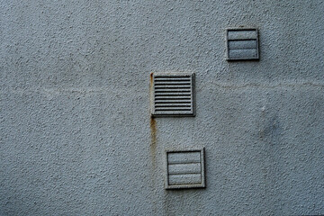 Grey weathered wall with exit points of air duct system. Construction industry.