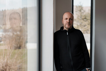 man leaning against a wall and looking seriously into the camera