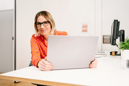 business woman with glasses and laptop looks into camera