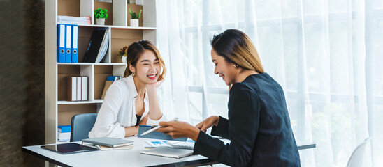 Two Attractive Asian businesswoman who talks with female friend, working in office.