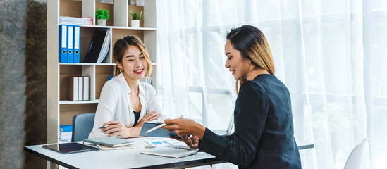 Two Attractive Asian businesswoman who talks with female friend, working in office.