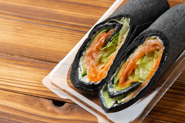 Black tortilla wrap with salted salmon and vegetables