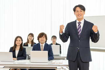 セミナーの男性講師とスーツ姿の男女（ガッツポーズ）
