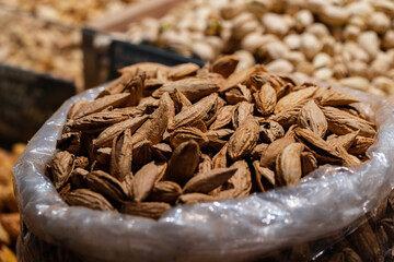 Unpeeled almonds in a sack bag in market for sale