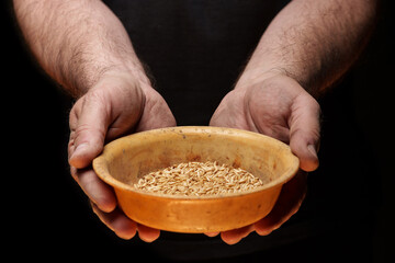 Close up of male hands holding small amount of wheat seeds. Lack of food and hunger concept