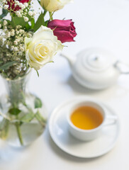 Vertical high angle closeup of white rose with tea cup and teapot in background (selective focus)