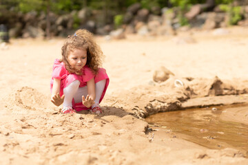 little beautiful girl playing in sand, building tower, castle on coast, seaside. cute child in sandbox in summer. baby toddler and sandcastle outdoor