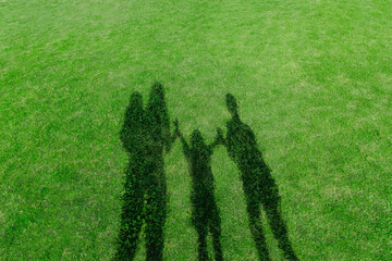 緑の芝を背景にした親子で手を繋ぐ影、幸せ、家族、絆、愛情のイメージ