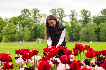 Portrait teenage girl walking in spring park with colorful flowers outdoors