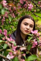 Portrait teenage girl walking in spring park in blooming apple trees