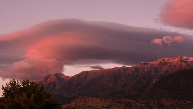 Lenticular clouds during colorful sunset over Timpanogos Mountain in Utah moving in time lapse.