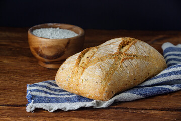 Rustic fresh loaf of sourdough bread with flour on wooden table