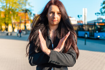 Fototapeta premium Pretty business woman with her arms crossed at her chest demonstrates break the bias symbol of woman's international day.Woman show solidarity,breaking stereotypes, inequality.sunset city outdoors.
