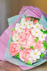 beautiful bouquet made of marshmallows in the form of pink rose flowers. A bouquet of marshmallows. Handmade work. Decorated in the form of a bouquet. In colored craft paper.