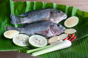 Fresh tilapia fish with lemongrass, lemon and chili on banana leaf. Asian food concept
