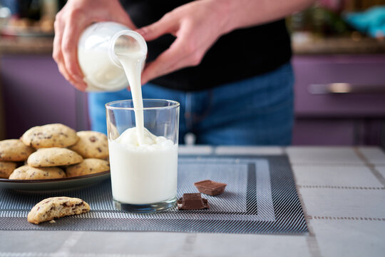 Pouring milk in glass with Homemade chocolate cookies on background