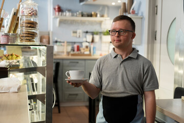 Caucasian man with down syndrome walking and carrying a cup of coffee