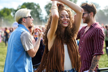 Young woman dancing and  having fun on music festival with friends in the background
