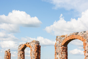 An old, dilapidated stone and brick building in a meadow under a dramatically cloudy sky. Old rural property.