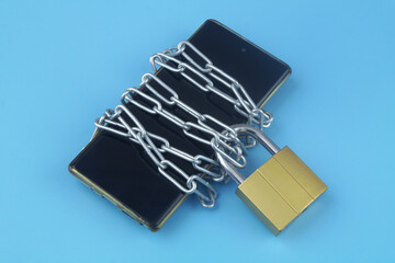 Privacy and data safety concept. Chained smartphone with padlock on blue background.	