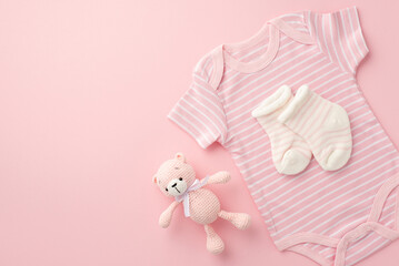 Baby accessories concept. Top view photo of pink bodysuit socks and knitted teddy-bear toy on isolated pastel pink background with copyspace