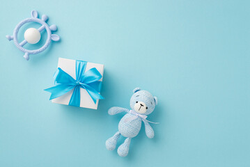 Baby boy concept. Top view photo of giftbox teether and knitted teddy-bear toy on isolated pastel blue background