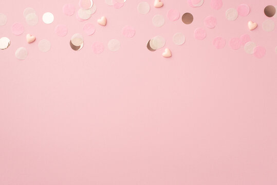 Top view photo of pink hearts and shiny confetti on isolated pastel pink background with empty space