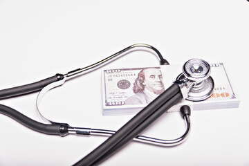 Medical concept - stethoscope over the dollar bills isolated on white background.