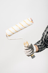 A male builder in a hard hat holds a paint roller on a white background, close-up