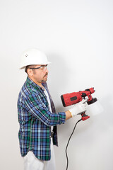 Male builder with electric spray gun on white background