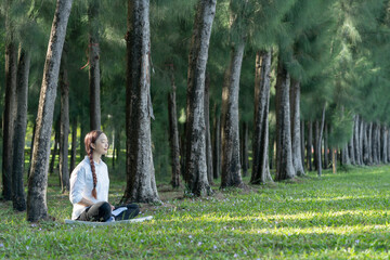 Beautiful young woman doing meditate and yoga in the park.