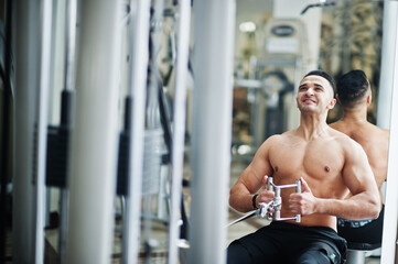 Muscular arab man training in modern gym. Fitness arabian men with naked torso doing exercises .